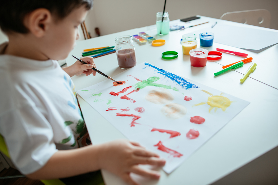 Мальчик левша рисует красками