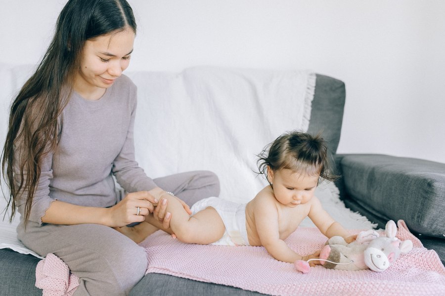 Мама делает массаж ног своей дочке на диване