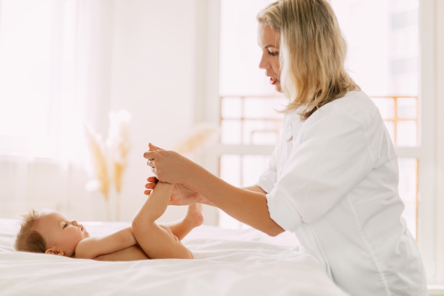 Мама делает массаж маленькому ребенку на кровати