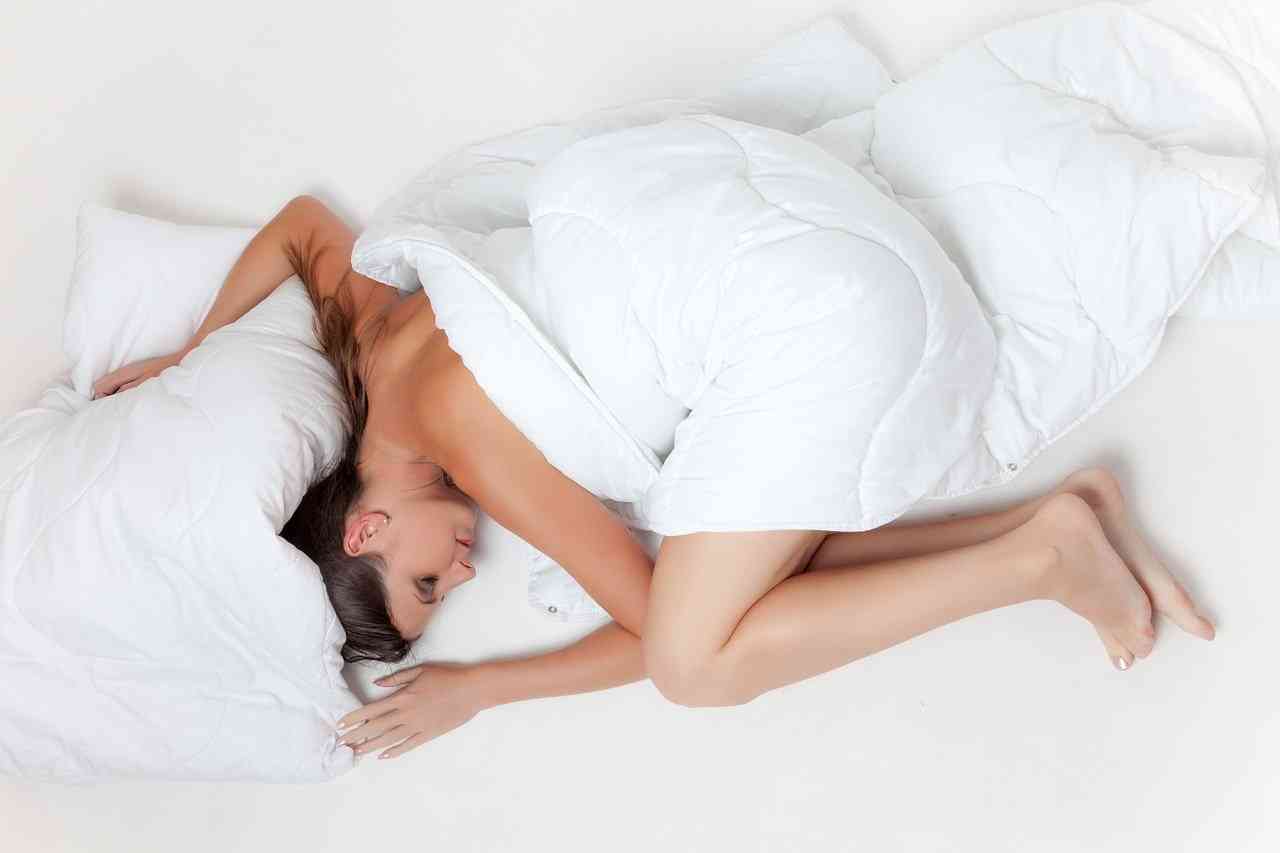 Девушка лежит в белой кровати под белым одеялом