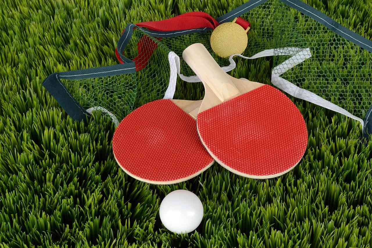 Красные ракетки для настольного тенниса и мяч в руках человека