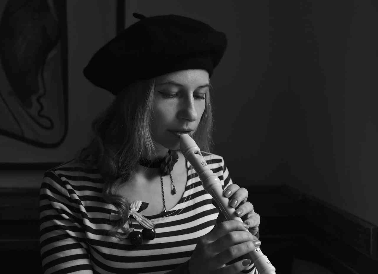 Черно-белая фотография девушки в берете играющей на флейте